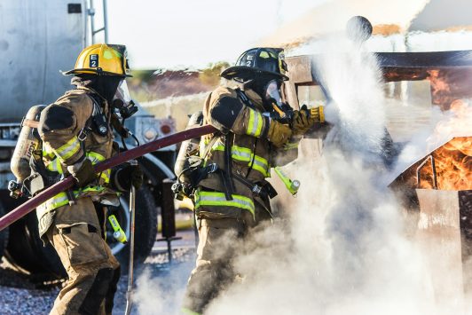 Firefighters spraying test fire with water hose
